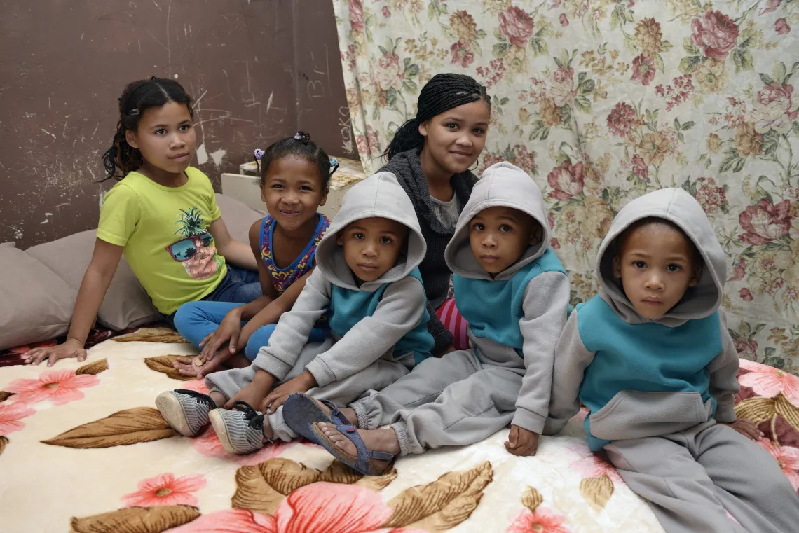 six young children sitting on a bed together