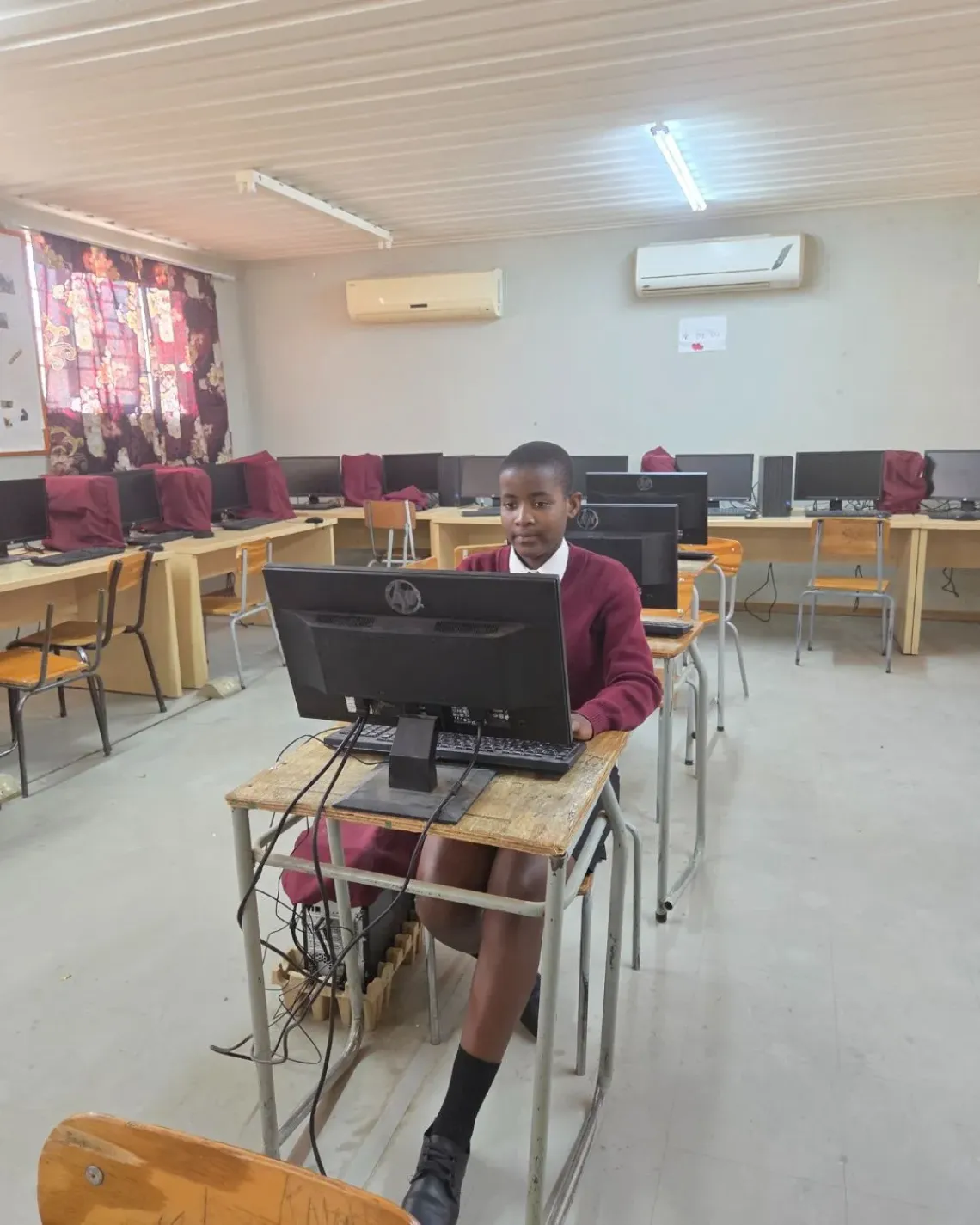 A girl learner sitting behind her desk working on a laptop