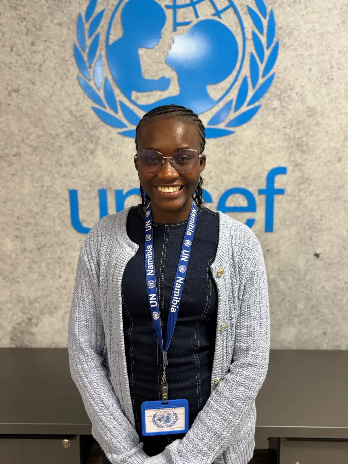 Young girl posing in front of a UNICEF Emblem