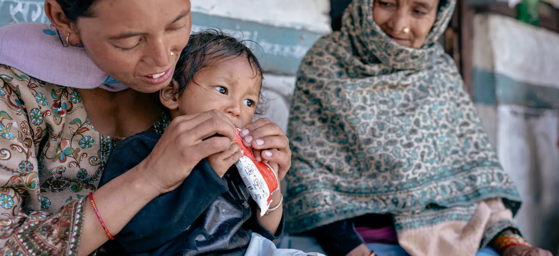 At the Tripurasundari Health Post in Dolpa District, 21-month old Nirajan Ukheda being fed Ready-to-Use Therapeutic Food (RUTF) by his mother Lal Kumari under the watchful eye of Female Community Health Volunteer Hans Kumari. 