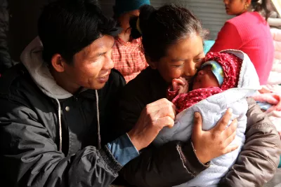 This image shows a family - a father and mother holding their newborn baby