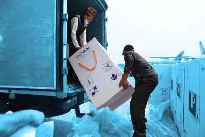 This image shows workers transporting COVAX branded boxes with COVID-19 vaccines