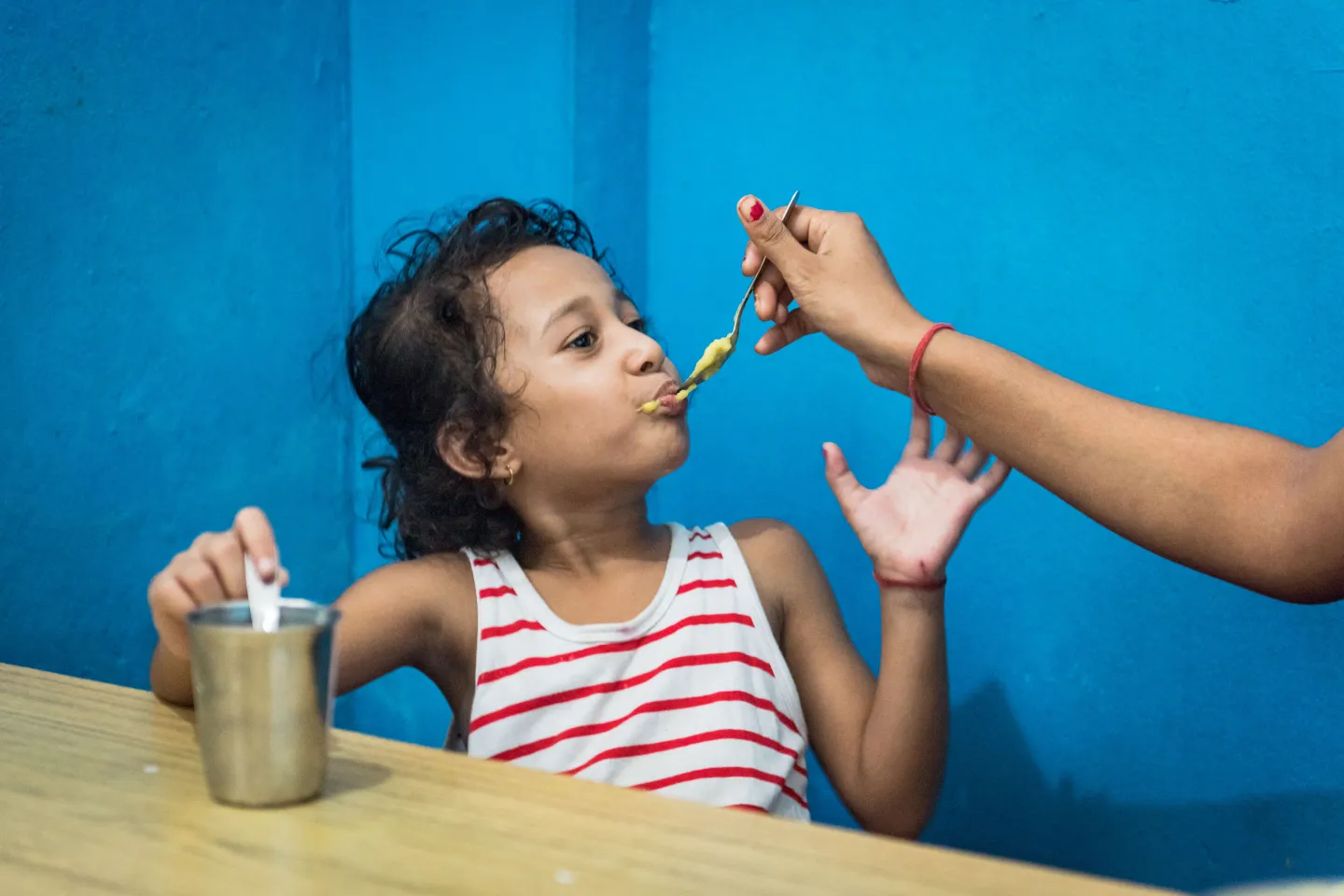 A young girl being fed by a spoon