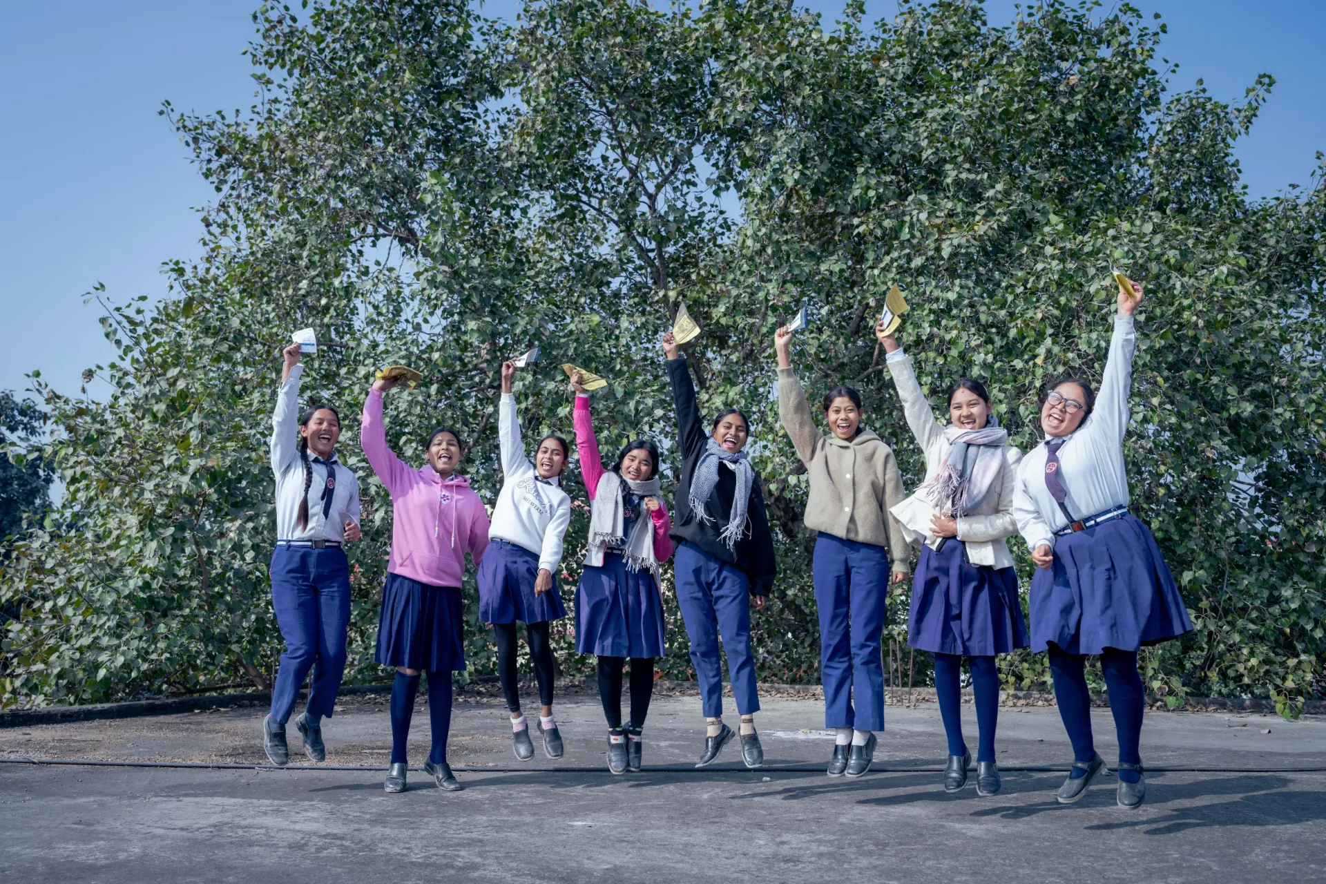 Elated girls pose with their vaccination cards for a picture.
