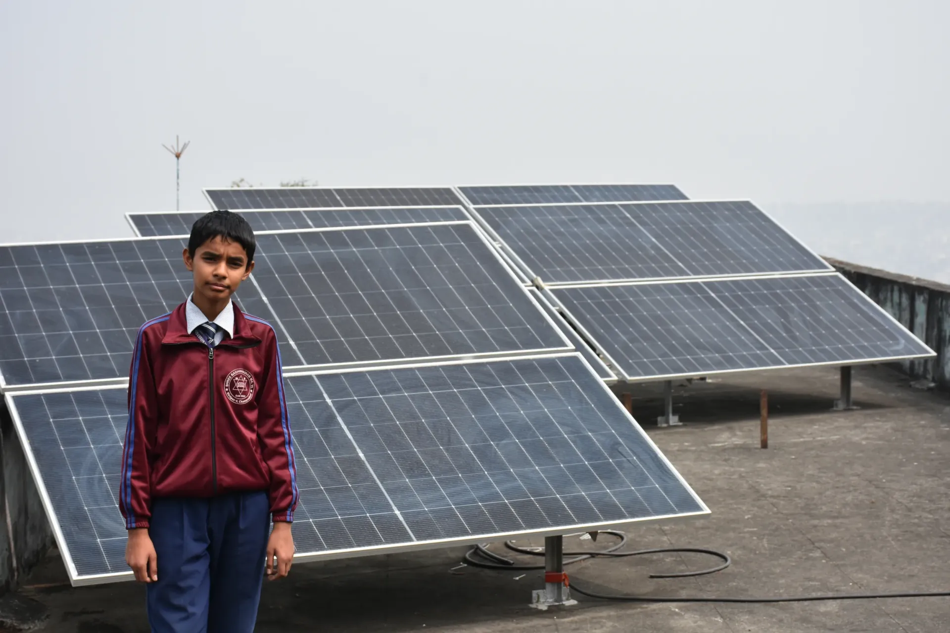 Biraj stands in front of the school's solar panels