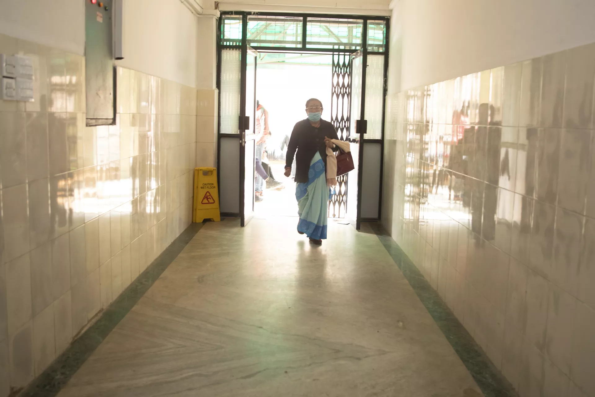 This image shows FCHV Durga Devi Shrestha walking in the Charikot Hospital