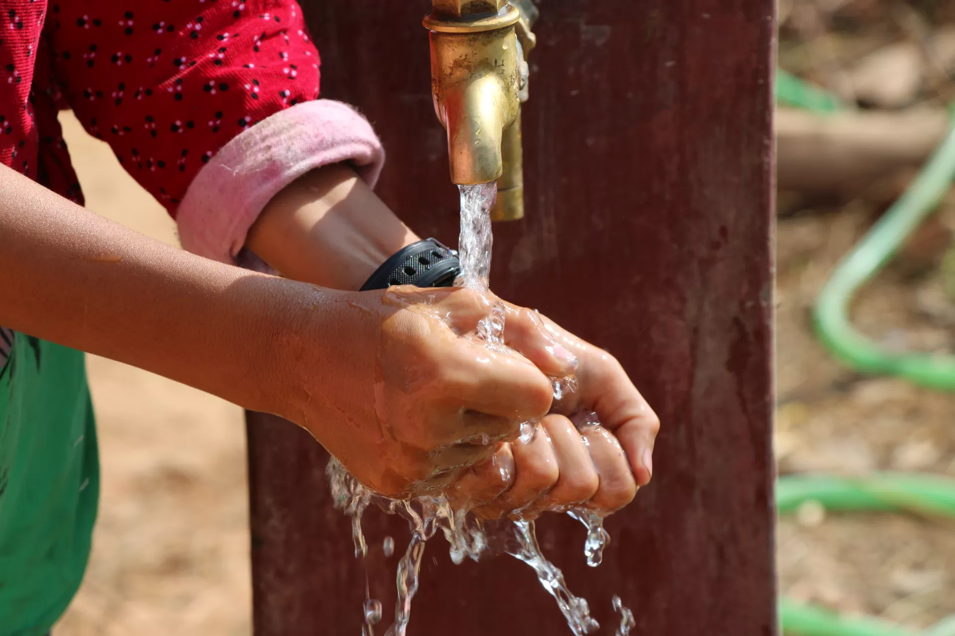 A young girl washing hands in the tap at her home in Chhage, Kavrepalanchowk