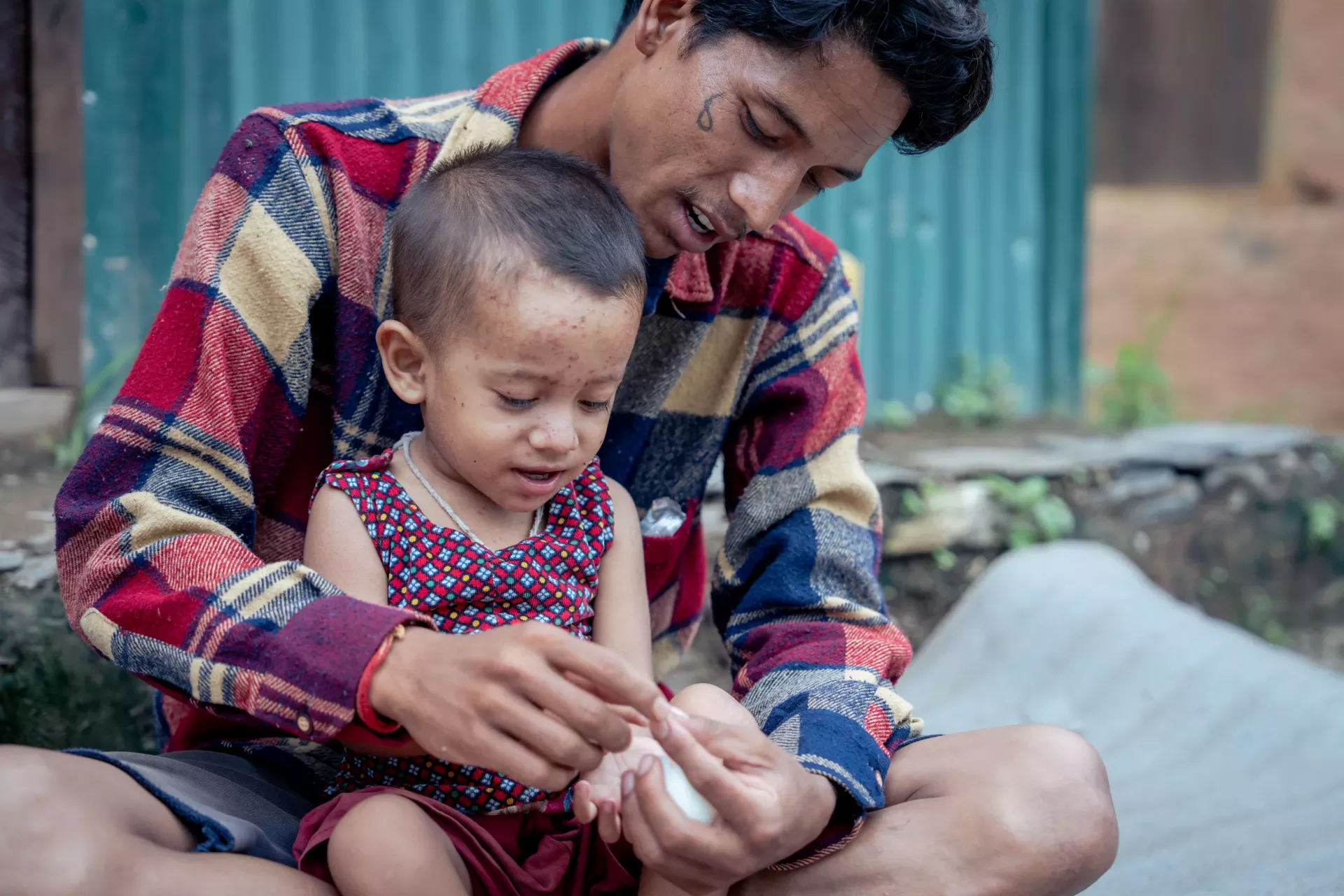 Shishir Sunar feeding his son Nithin in their home in Rukum West