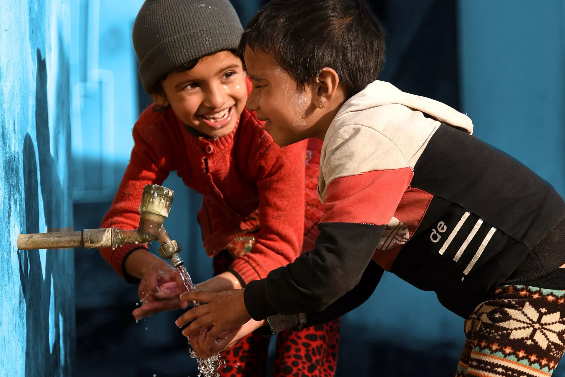 This image shows two children washing their hands at a tap