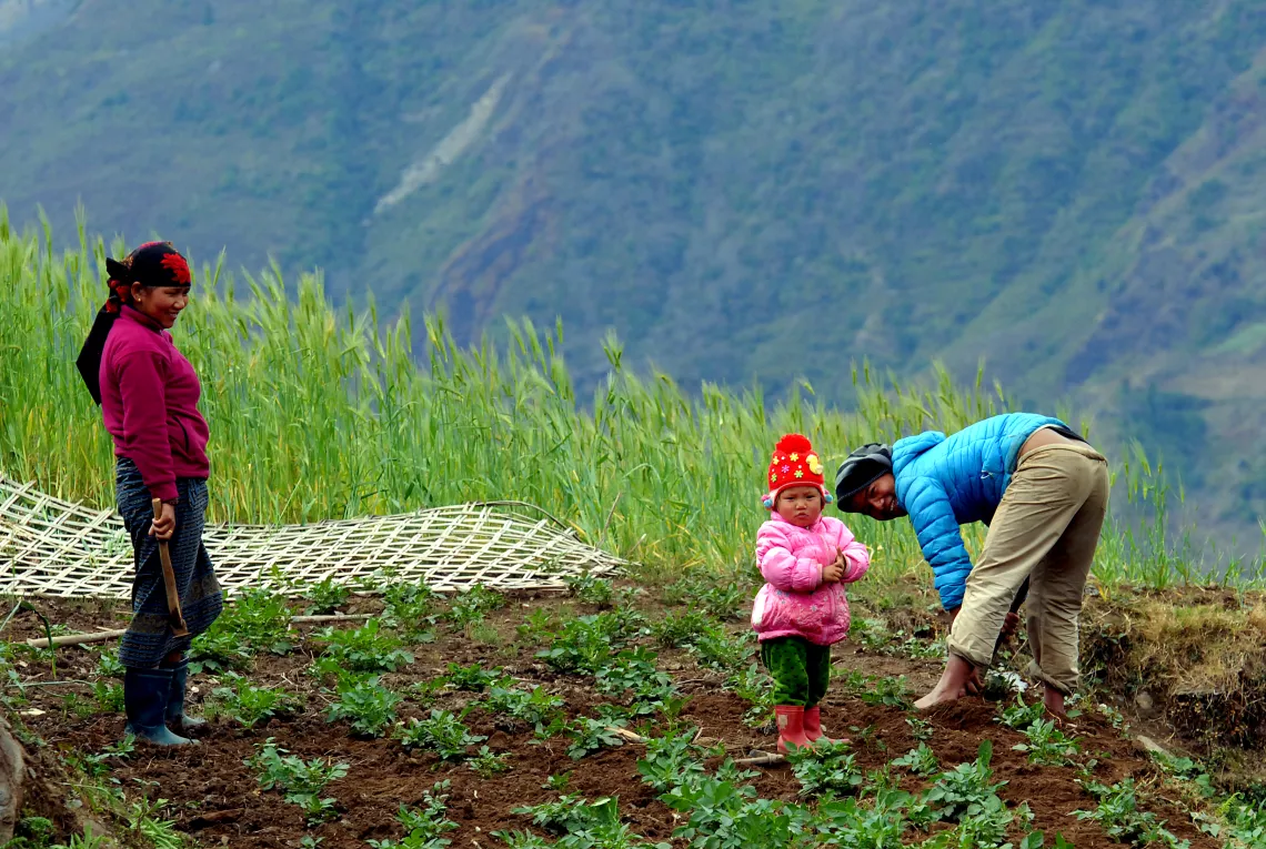 a child playing in the field with her parents