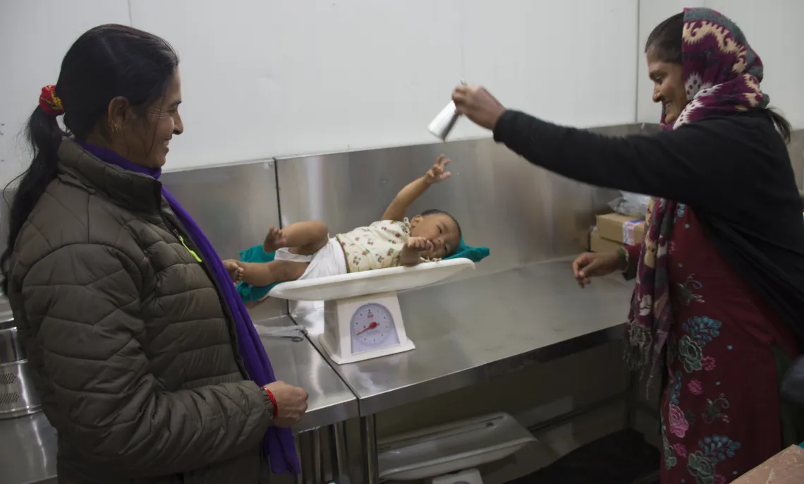 Midwives measure the weight of an infant 