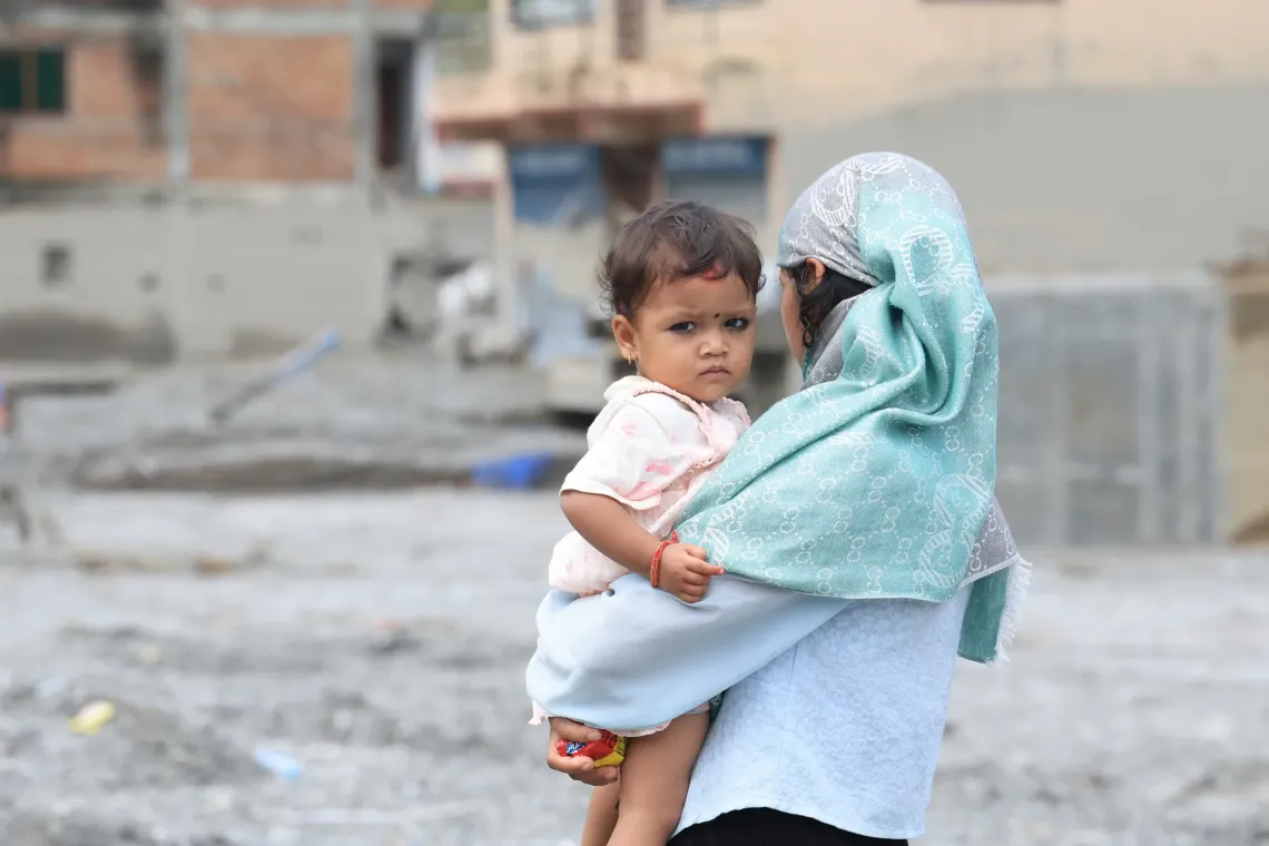 A girl carrying a small child looks over the devastation left behind by the floods