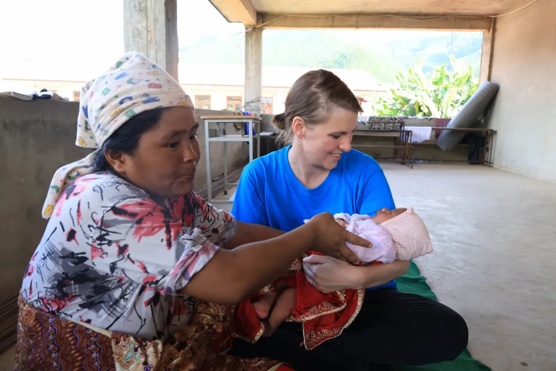 Nanu Maya gently hands over her newborn son to UNICEF personnel.