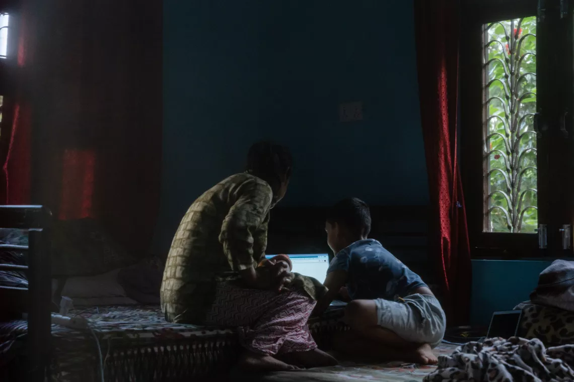 Tika Subedi and her son look at a laptop in their home in Surkhet District in western Nepal. 