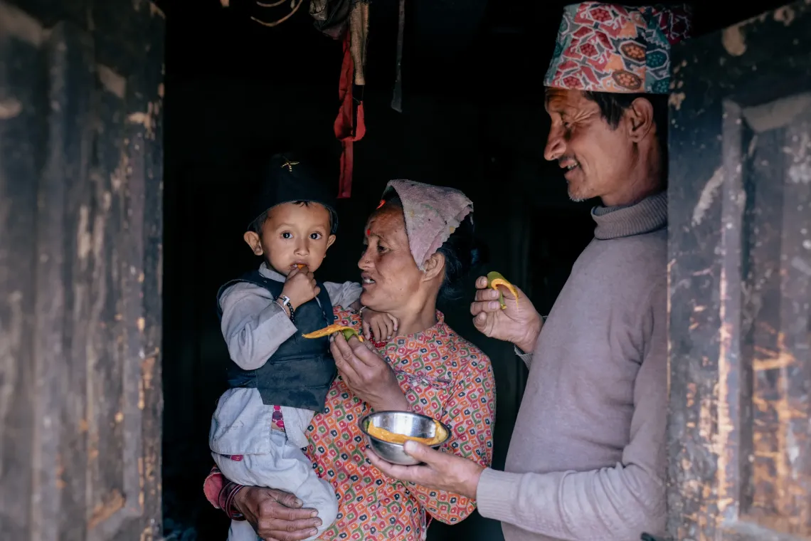 In Juphal in Dolpa District, two-year-old Kishor Shahi eats mangoes with his mother Lalita and father Hari. Kishor had previously been diagnosed with severe acute malnutrition, but was able to recover successfully following an intensive Ready-to-Use Therapeutic Food (RUTF) intervention.