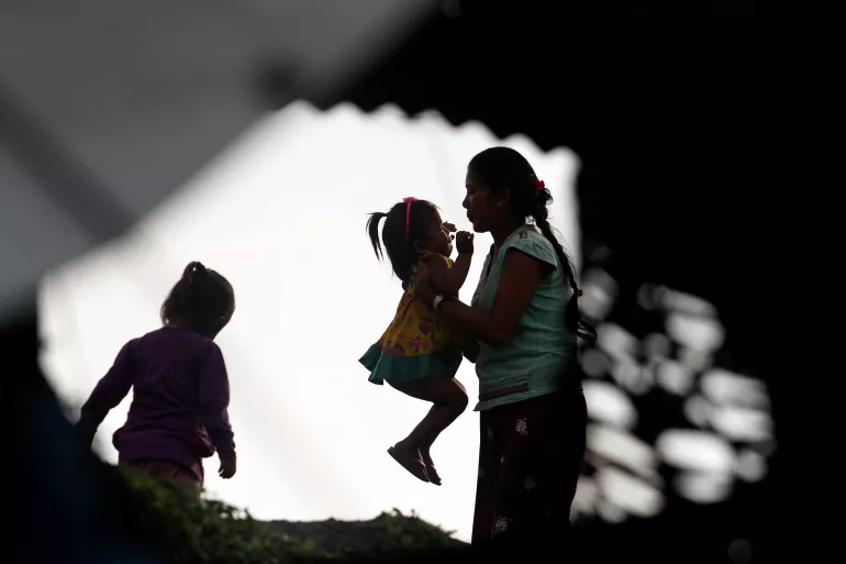 This image shows a silhouette of a mother lifting up her child