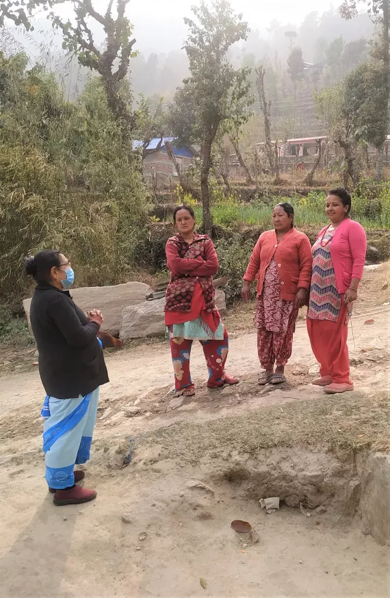 This image shows FCHV Durga Devi Shrestha interacting with community members