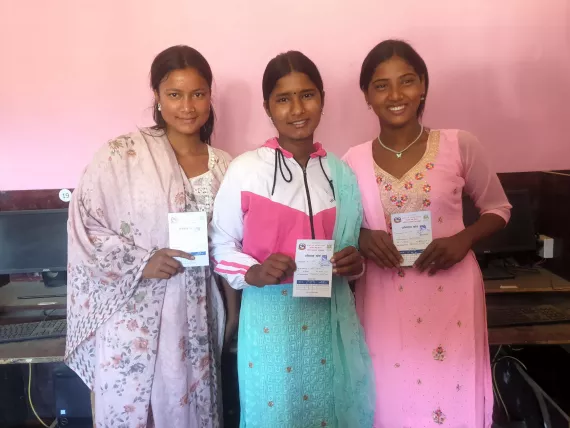 three out of school girls posing with their vaccination cards