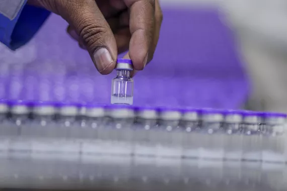 This image shows a hand picking out vaccine vials from a line-up