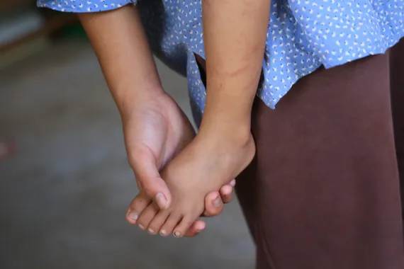 On 27 August 2026, Sonika (13) holds her younger brother Sajan (3)'s foot in a school in Nuwakot District where the family have been staying since escaping the floods that destroyed their home and village on 26 August.