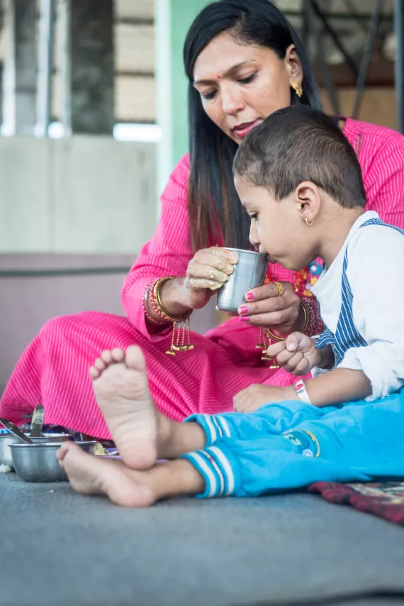 a mother helps a child drink water