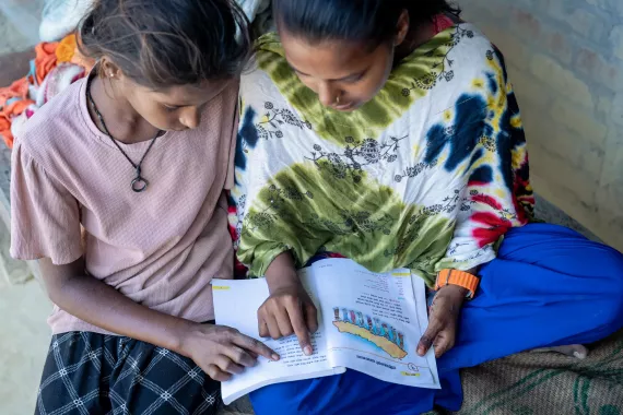 Laxmi reading book with another girl beside her