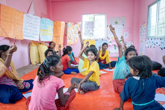 SAGE participants in the classroom sitting and raising hands