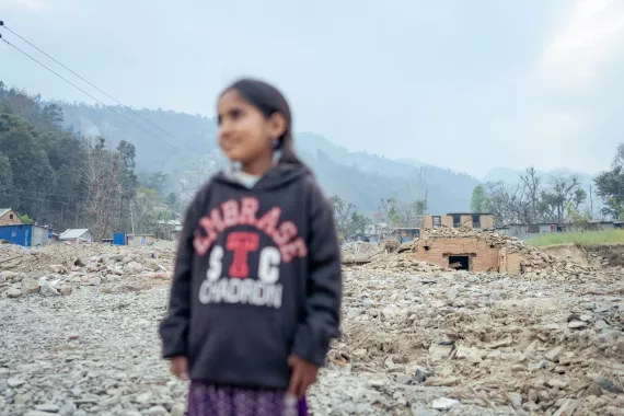 Radhika standing against a horizon of rubble caused by the floods