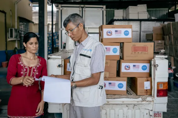 At the Government's Provincial Health Logistics Management Centre in Birendranagar, support staff Sushila Chapagain helps UNICEF staff to load boxes of Ready-to-Use Therapeutic Food (RUTF) - provided by the US Government - onto a vehicle to be delivered to Dolpa District.