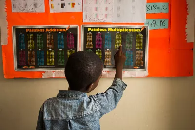 A boy reading a multiplication table pasted on the wall.