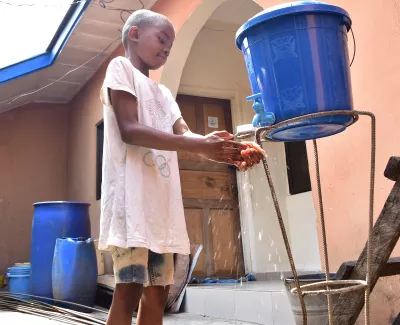A boy washes his hands at a handwashing station in his home