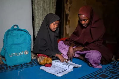 A girl reading a book to a woman. 