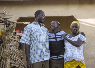 A boy stands with his parents.