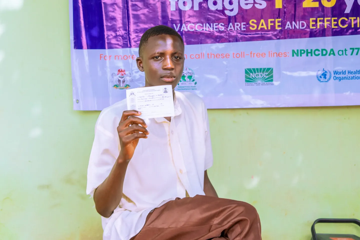 A boy holding a vaccination card
