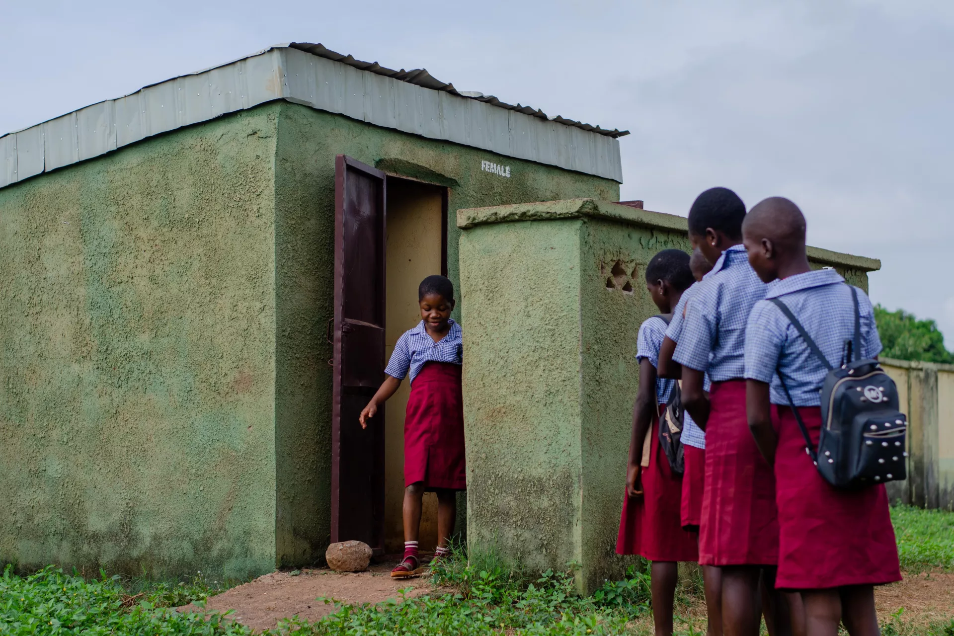 A group of girls standing near a toilet