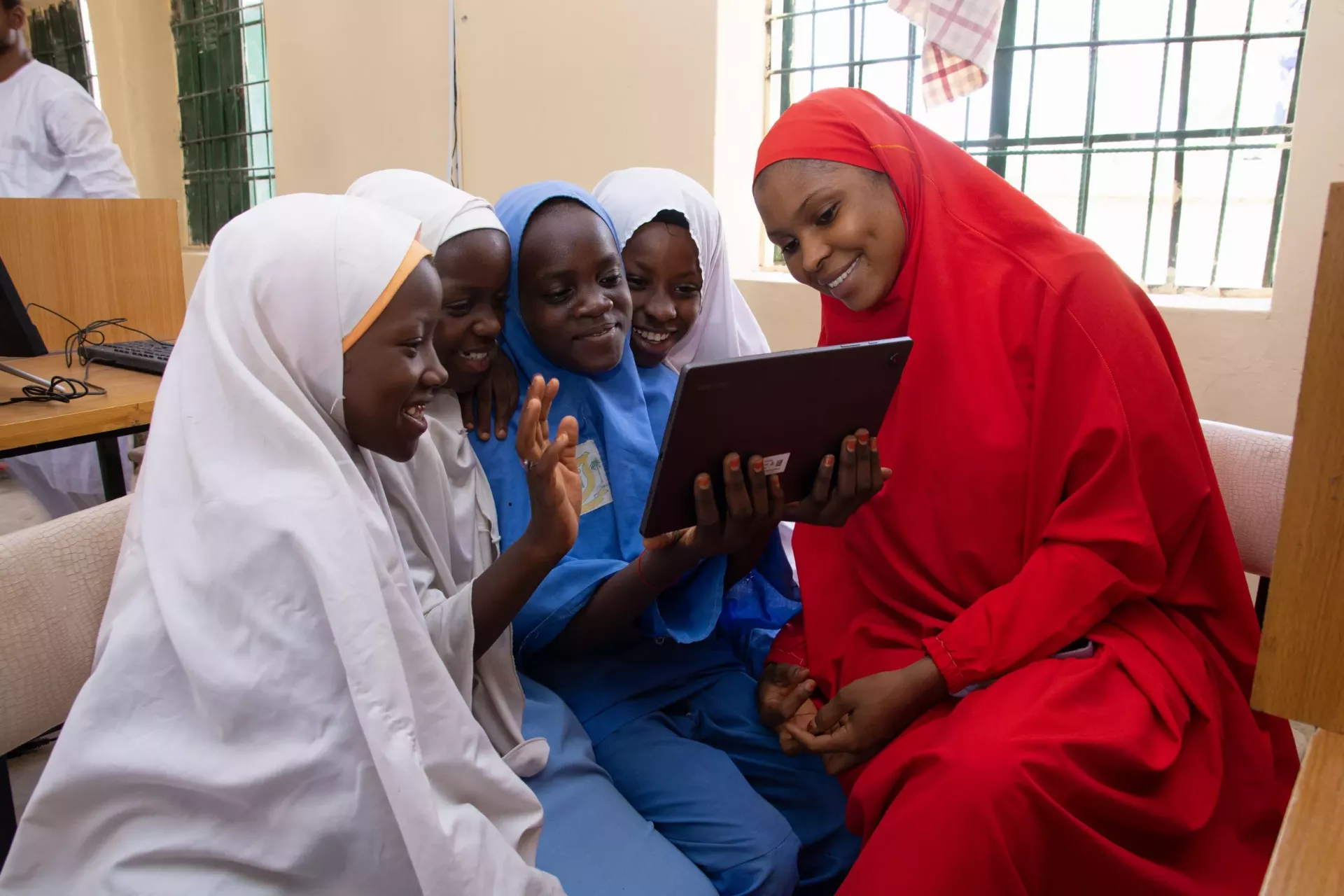 Students using a tablet with their teacher