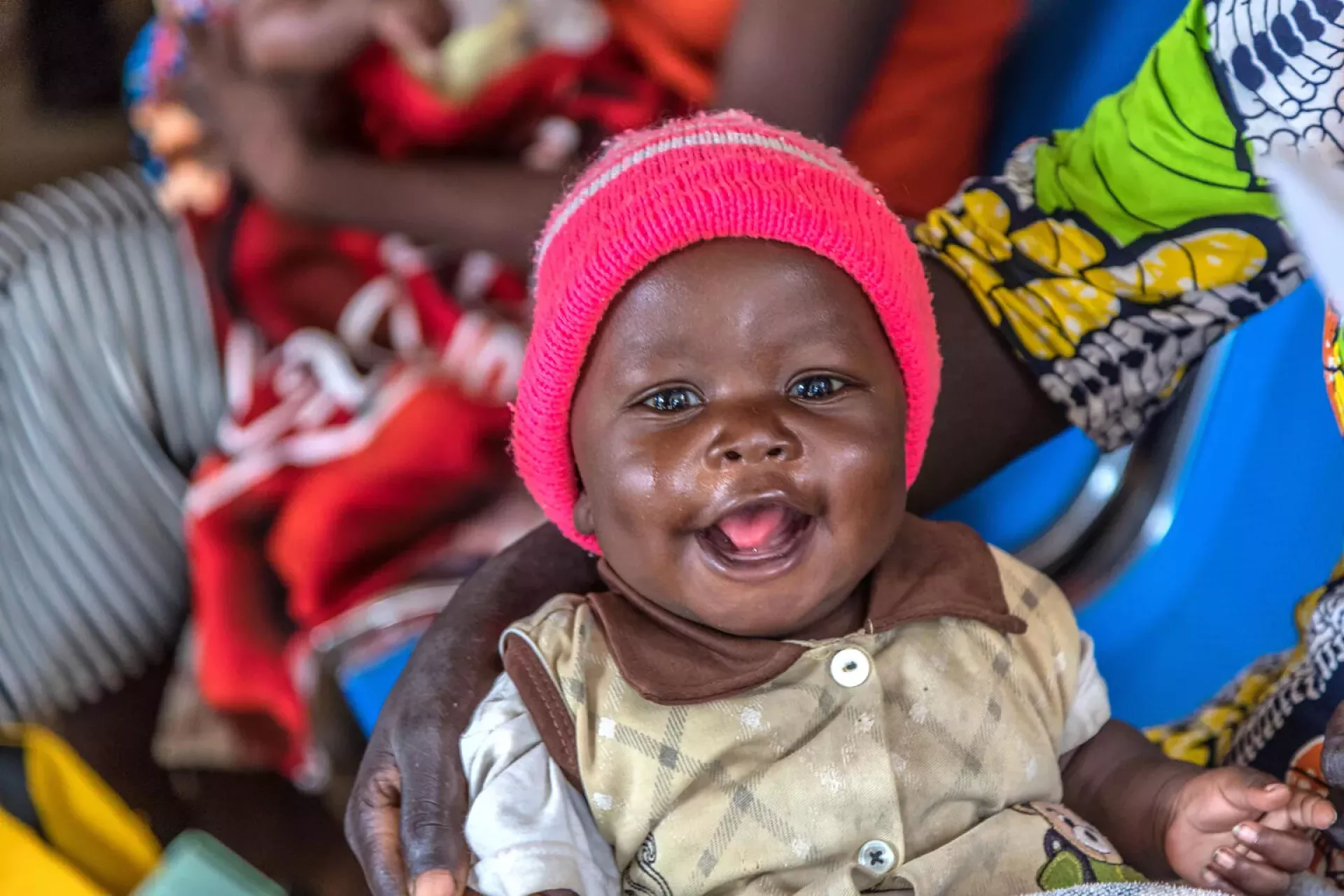A happy baby smiling in the hands of parent