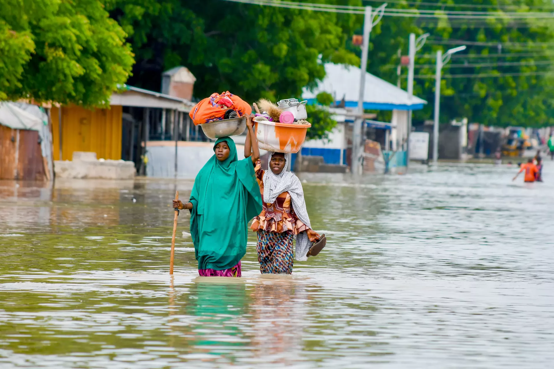 2 girls wading through flood waters
