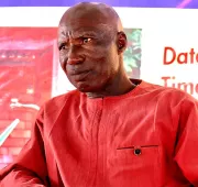 A man in a red dress looking at the camera.