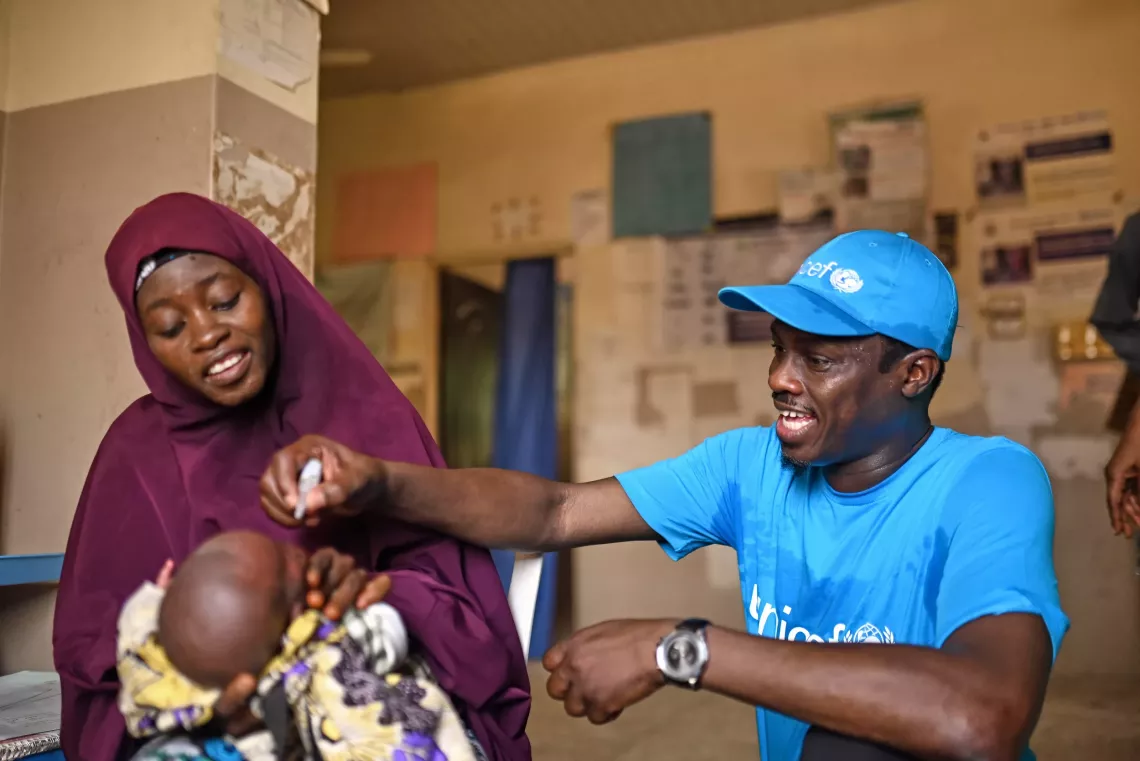 A woman holding a baby receiving vaccination. 