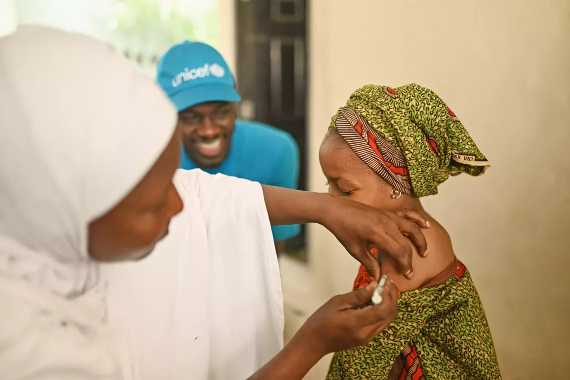 A woman giving vaccine to a girl. 