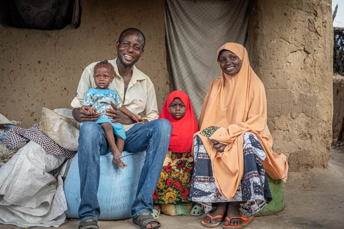 The Audu family sitting in front of their hut