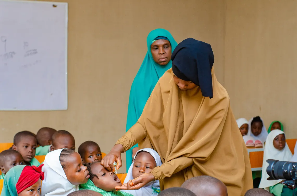 A health worker immunizing children in a classroom