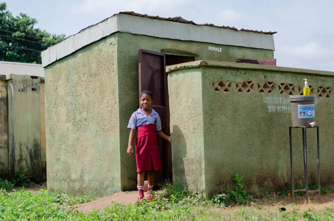 A girl standing beside a toilet