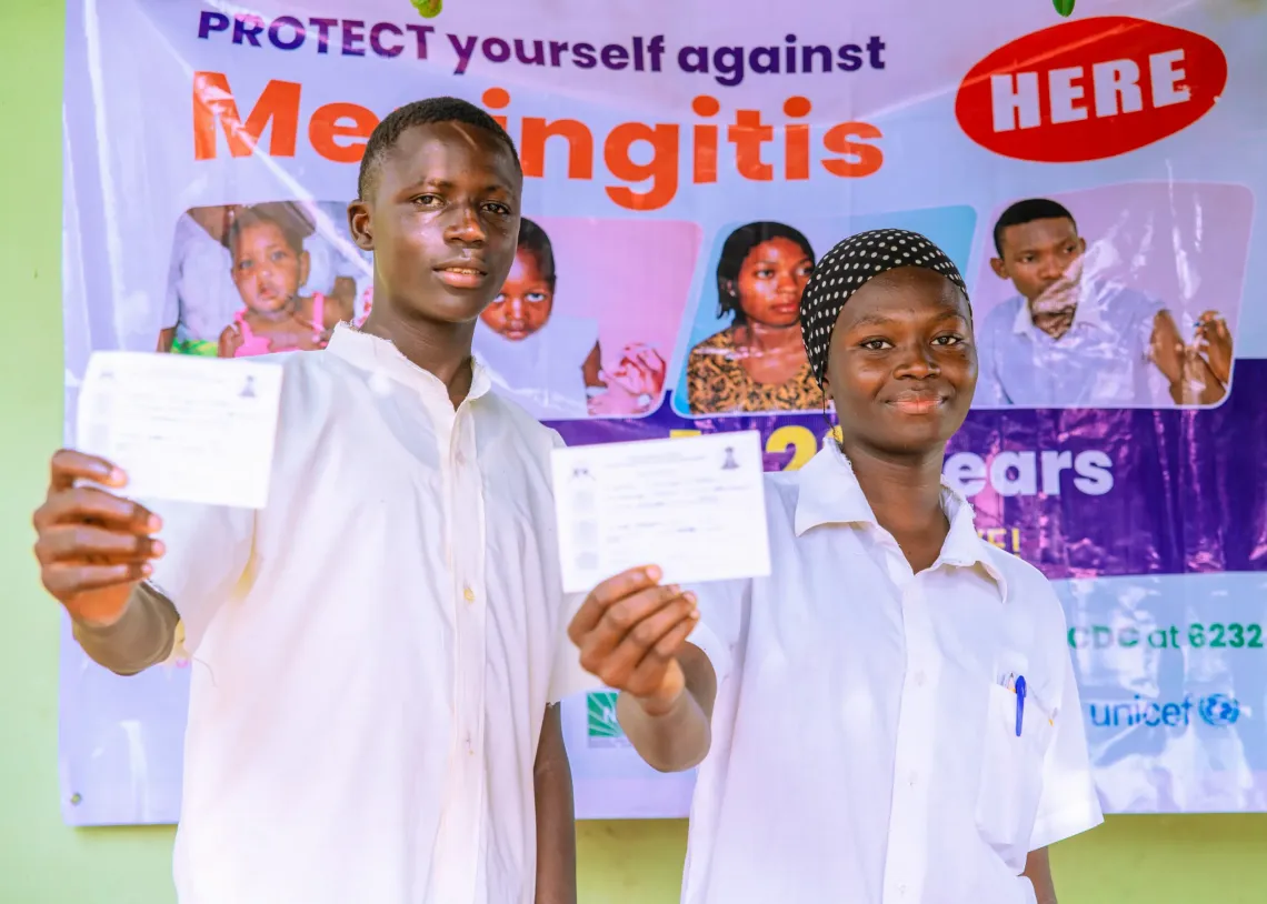 A boy and a girl holding a vaccination card