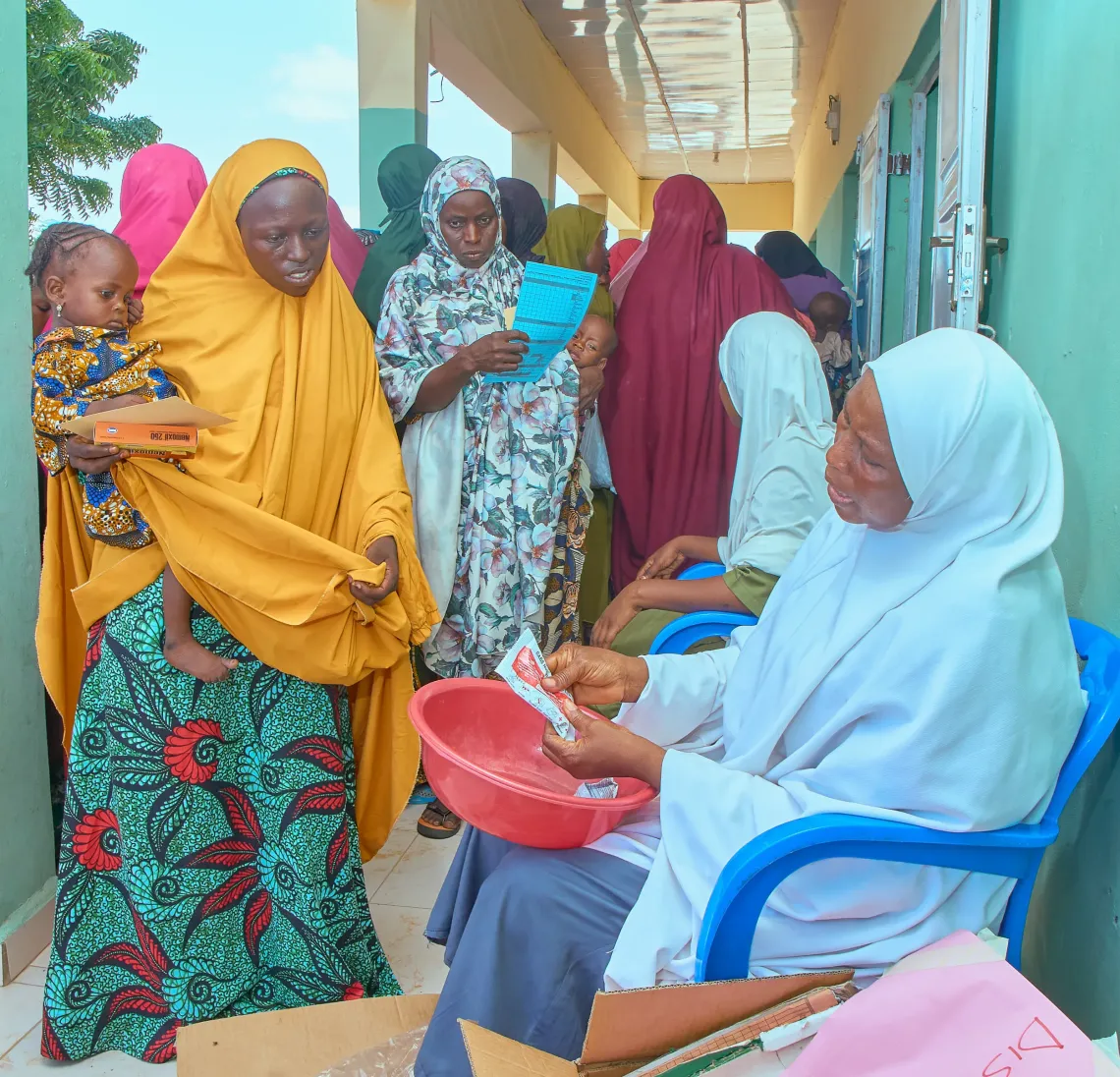 Rabiatu Kabiru, 24 months old and with severe acute malnutrition (SAM), receives continued nutrition support through 14 sachets of Ready-to-Use Therapeutic Food (RUTF) collected by her mother, Mariya Bello, 20, at Jibia Primary Healthcare Centre.