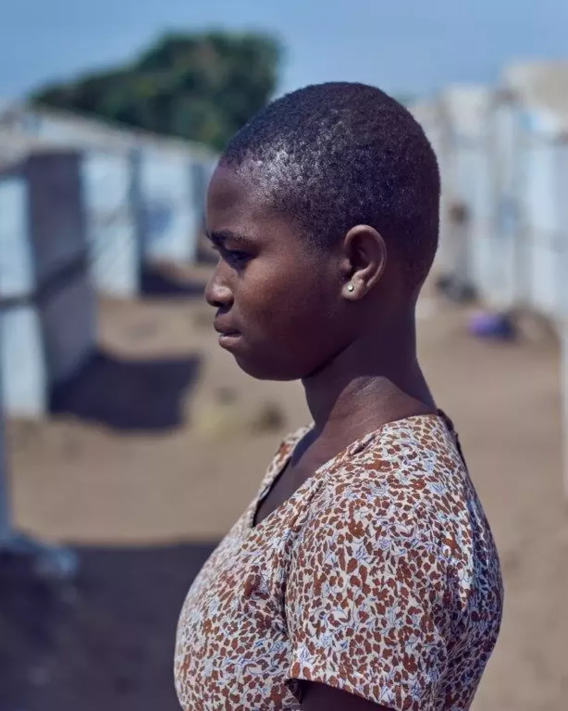 A young girl standing in front of a house at the IDP camp.