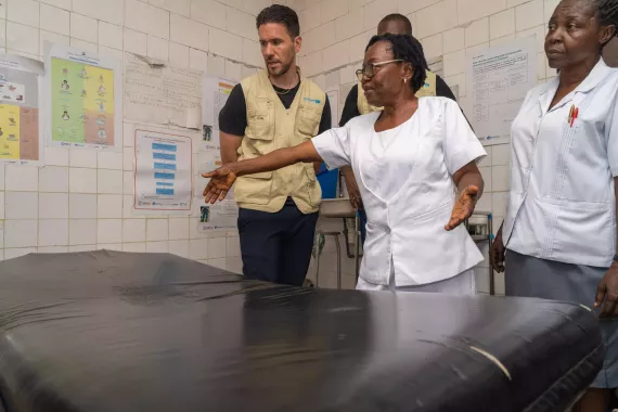 A woman in a white uniform using a man a delivery bed. 