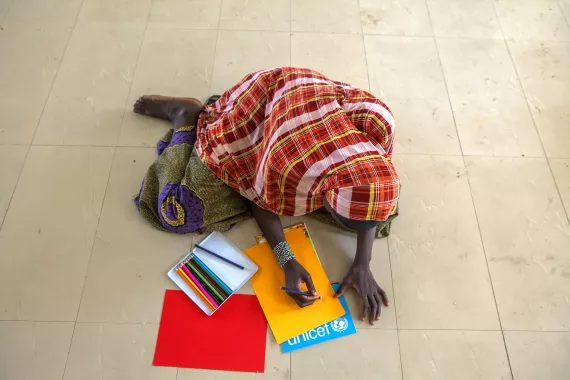 A girl drawing on coloured paper in an IDP camp in northeast Nigeria.