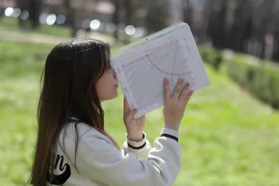 Девојче користи хипсометар за мерење висина на дрвја на настан за климатска акција организиран од УНИЦЕФ